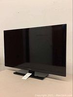 Full view of the Insignia 32-inch TV sitting on a table, turned off, showing the screen, bezel, and stand.