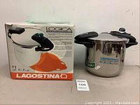 Front view showing the Lagostina pressure cooker with original box, cooker has stainless steel body with black handles and lid knob.