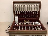 Full set displayed open in brown and white velvet-lined wooden box, showing knives in top rack and all other pieces below.