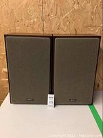 Front view showing pair of vintage Advent box speakers with gray fabric fronts and wood cabinets.