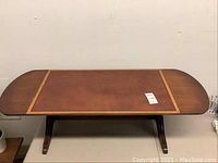 Front view of the antique drop leaf coffee table showing the rectangular top with rounded drop leaves and inlaid border.