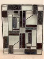 Front view of stained glass window panel showing geometric design with various textured and colored glass pieces.