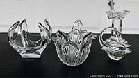 Clear art glass items including a pair of swan shaped candy bowls, a Waterford bowl with floral petal design, a free form glass candy bowl, and a pillar style candlestick.