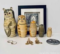 Full view of all items including nesting dolls, framed drawing, earrings, and pewter ornament.