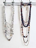 Multi-strand vintage glass bead necklace on right side, featuring colorful small round beads in reds, blues and browns, and some additional necklaces on left side including the Chan Lu layering necklace with white and clear crystals and mixed charms
