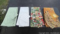 Full display of the four tablecloths and napkins laid out flat and folded.