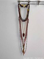 Four Chan Lu multi-strand layered necklaces with beads and pendants hanging from a display rack.