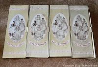 Four Little Women dolls in original boxes arranged side by side showing front box art with character illustrations