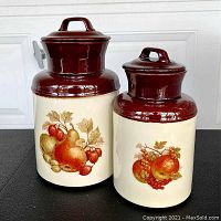 Front view of two McCoy ceramic canisters with fruit motifs and brown lids