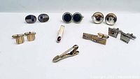 Full set of 3 tie clips and 5 pairs of cuff links displayed on a white surface.