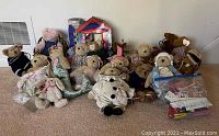 Group of 14 teddy bears including Muffy Vanderbear line with a bag of accessories and wooden dollhouse furniture in background.