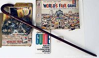 Photo showing all items including the board game, puzzle, guidebook, wooden cane, and matchbooks arranged on a white surface.
