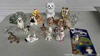 Top-down view of assorted animal figurines including glass squirrel, turtle, multiple ceramic cats and dogs, and a boxed Whimsies porcelain dog figurine.
