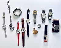 Full view of all 13 watches included in the lot laid out flat, showing different styles, bands, and faces including wristwatches and pocket watches.