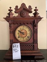 Full front view of the Ansonia wooden mantle clock showing ornate wooden design and clock face.