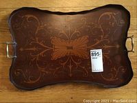 Top view of antique wood tray showing detailed floral and leaf wood inlay pattern and brass handles at each end.