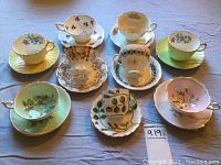 Top view of nine bone china tea cups and matching saucers, showing various floral and gold trim patterns.