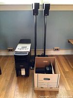 Lot overview showing two satellite speakers on stands, the Acoustimass bass module, and a box containing wireless surround components.