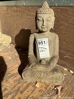 Full view of the small sitting Buddha statue with label showing lot number and description.