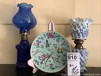 Group view of cobalt blue lamp, milk glass lamp, and Famille Rose plate front view
