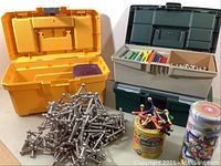 Wide view of five containers holding Geomag magnetic construction pieces including large magnetic rod assemblies and storage boxes.