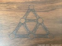 Close-up of wooden box lid with Geomag logo and magnetic construction illustration etched on surface.