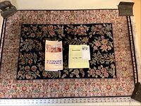 Full view of the rug showing the floral pattern, color scheme, and size with measurement scale and included documentation (receipt and certificate)