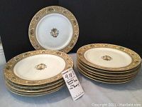 Stack of 12 dinner plates with The Beverly pattern, showing gold and fruit decorated rim and central urn motif.