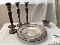 All items displayed on white cloth: four candlesticks, platter, sugar bowl and tongs