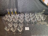 Full collection of 32 assorted crystal and glass wine, champagne, and apritif glasses displayed on a surface, showing variety and quantity.
