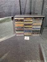 Photo of the stainless steel box with approximately 90 CDs arranged in five vertical columns showing visible spines.