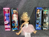 Full view of antique doll and four Medline nurse dolls in original boxes arranged side by side