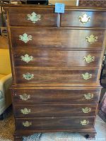 Front view of full dresser showing five large drawers and two smaller top drawers with brass pulls and floral wood carvings on corners.