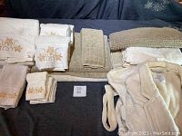 Overview of embroidered towels, assorted towels, bath rug, and bathrobe displayed on bed