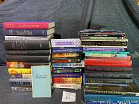 Stack of books showing a large quantity of various hardcover and paperback books including different authors and genres.