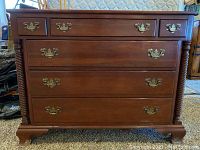Front view of five-drawer cherry dresser showing hardware and turned posts