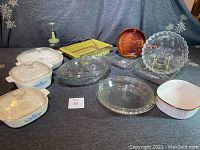 Full set of collectible cookware showing Corningware pieces with lids, a Pyrex pie plate, a yellow Addrock nut chopper, avocado roasting pan with rack, amber and clear glass baking dishes