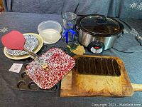 Full view of enamelware dishes, slow cooker, cutting board, glass, spatula, baking sheets and plastic container