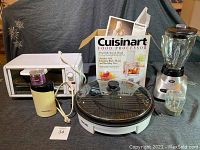 Full view of kitchen appliances showing all items including toaster oven, blender, coffee grinder, indoor grill, and boxed food processor with manuals.