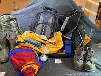 Photo showing the entire lot including multiple bags, boots, baseball, wallet, and camera case arranged on a surface
