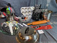 Full display of lot including utensils in stainless crock, Pyrex bowls, muffin pan, knife set, cooking pot, and other kitchen tools