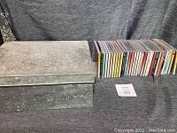 Photo showing a large stainless steel box and 33 CDs arranged beside it