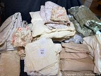 Photo of various bedding items including duvet covers with floral and solid patterns, sheets, comforter, mattress pad, and bedskirt all laid out for display.