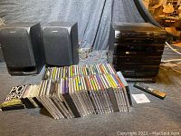 Photo showing entire lot including two black Sony speakers, several dozen CDs mostly classical music, multiple cassette tapes, and the stacked Sony mini stereo system with remote.