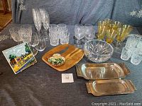 Wide view showing the entire lot including various glassware types, Dansk wooden cheeseboard, metal serving trays, decorative tile, and glass bowl