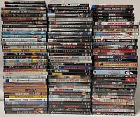 Stacked DVDs and Blu-rays showing titles across multiple genres such as Out of Sight, Die Another Day, Lady Snowblood, Evita, The Girl Next Door, Mad Max, and more.