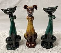 Front view of three figurines: two green cats and one brown dog; dog has chip on left ear
