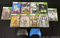 Overview photo showing 10 Xbox 360 game cases and 2 controllers arranged on black background.
