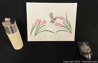 Lot overview showing hummingbird painting centered, herb mill left, and marble hook right on black background.