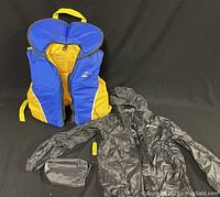Photo of Aqua Gear youth life jacket alongside Mountain Warehouse youth raincoat and its storage pouch